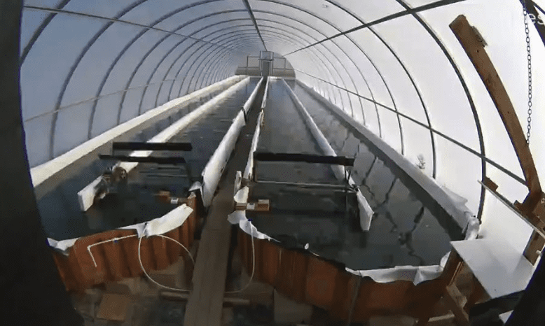 A roller coaster ascending a steep track inside a large enclosed structure.