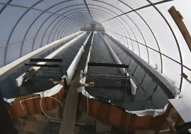 A roller coaster ascending a steep track inside a large enclosed structure.