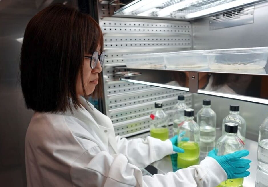 A woman in white lab coat working with bottles.